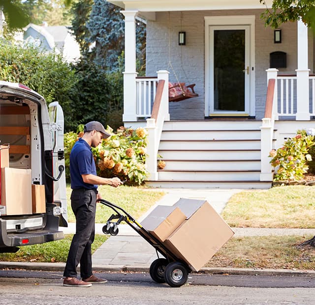 A last-mile delivery driver checking the address before delivering a box to a home